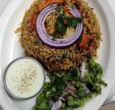 Chicken 65 biryani with an onion ring, raita and salad