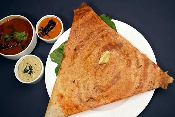 Mysore masala dosa folded into a triangle, with sambar and chutneys