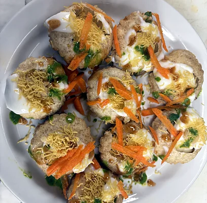 Puri chaat topped with yoghurt, sev, grated carrot and green chutney
